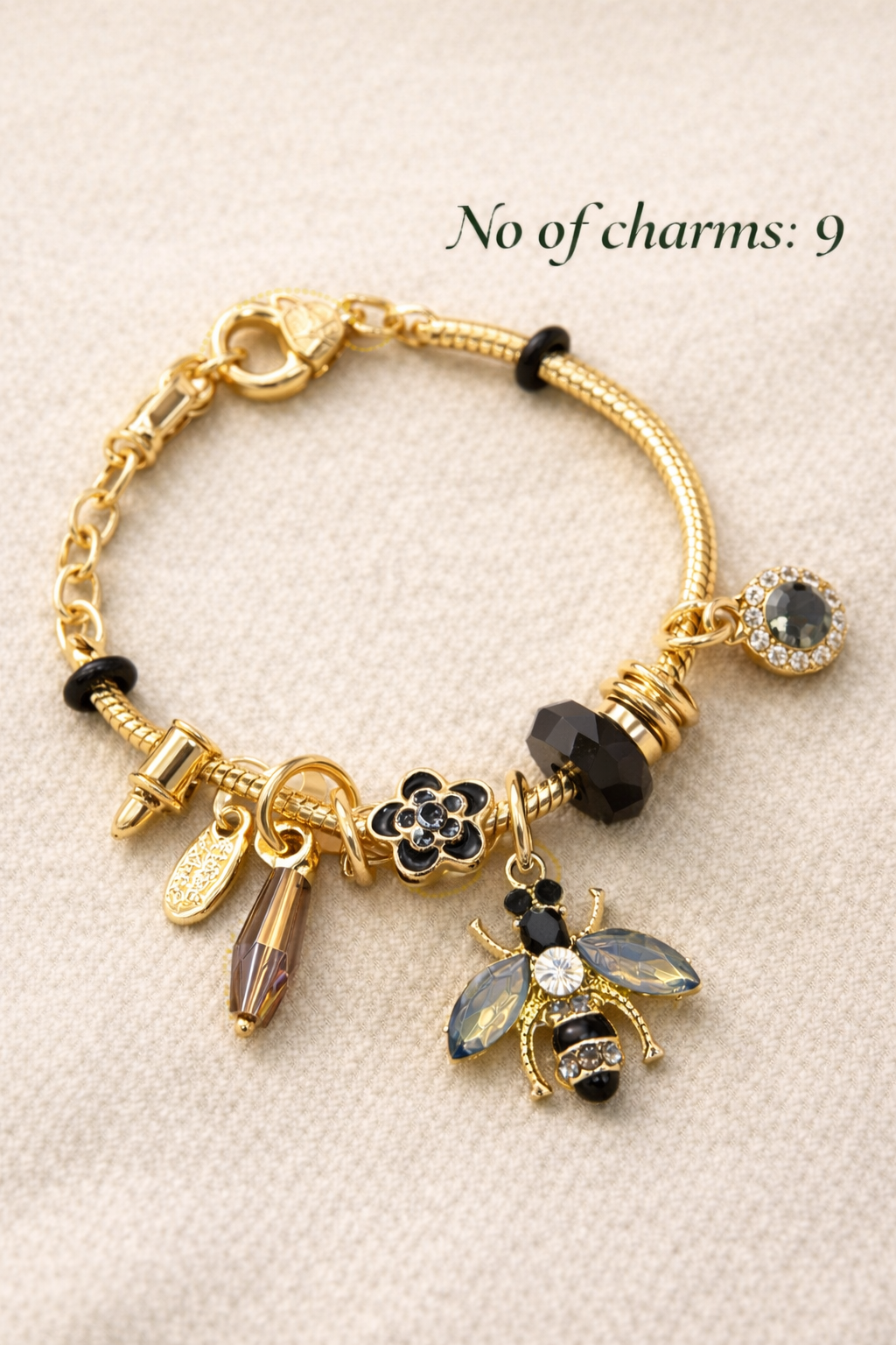 Anti-Tarnish, Ashaarya, Ashaarya Jewels, Ashaarya Jewellery, Gold bracelet with various charms on a beige background