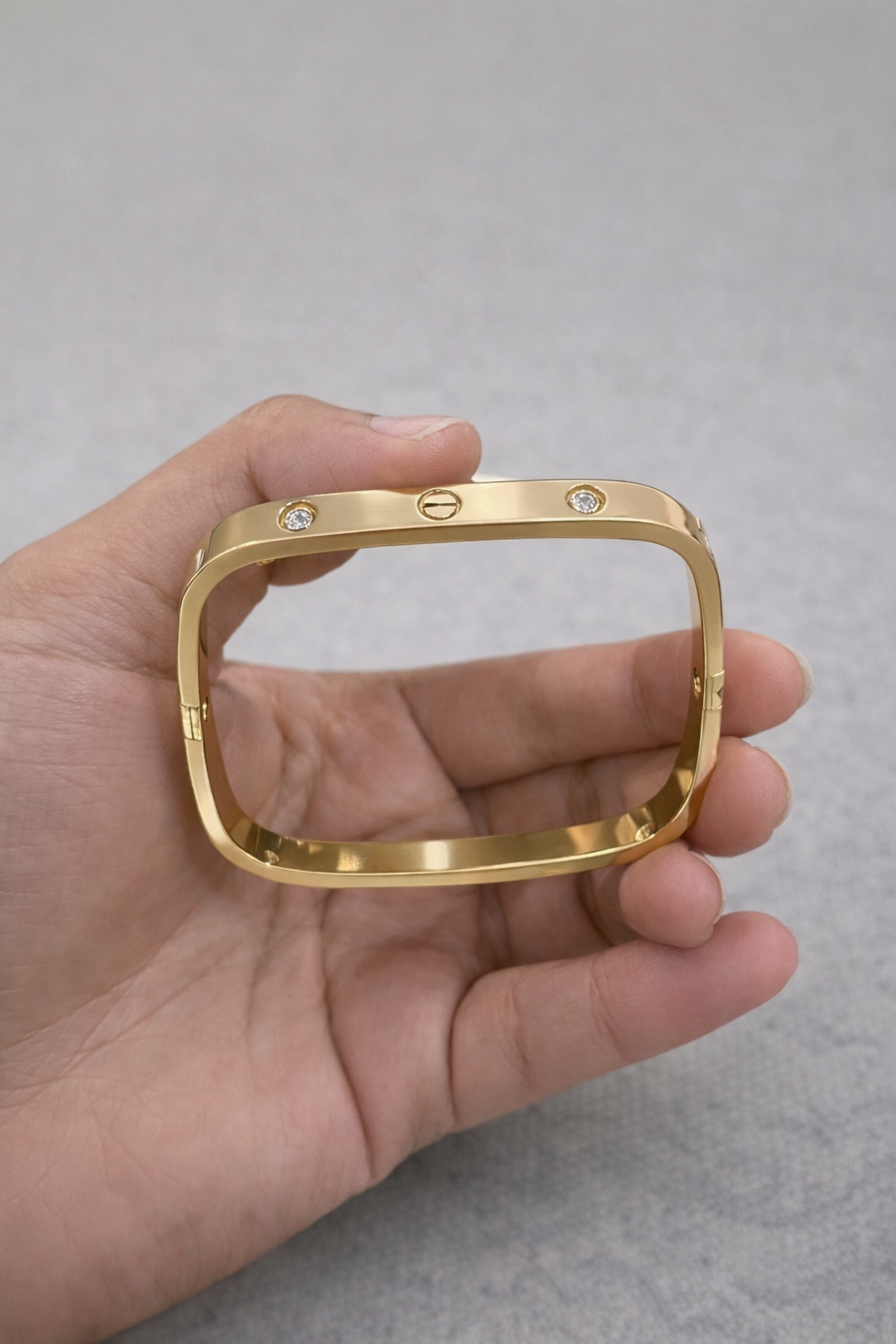 Anti-Tarnish, Ashaarya, Ashaarya Jewels, Ashaarya Jewellery, Gold bracelet held in a hand against a gray background