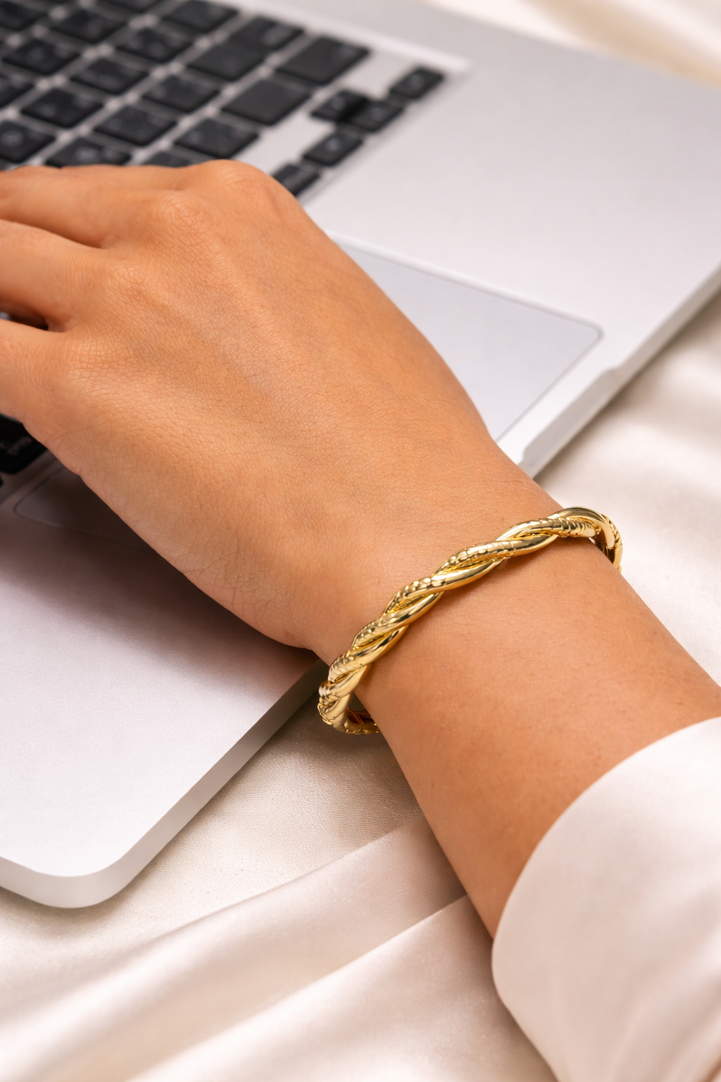 Anti-Tarnish, Ashaarya, Ashaarya Jewels, Ashaarya Jewellery, Hand wearing a gold bracelet using a laptop on a light surface