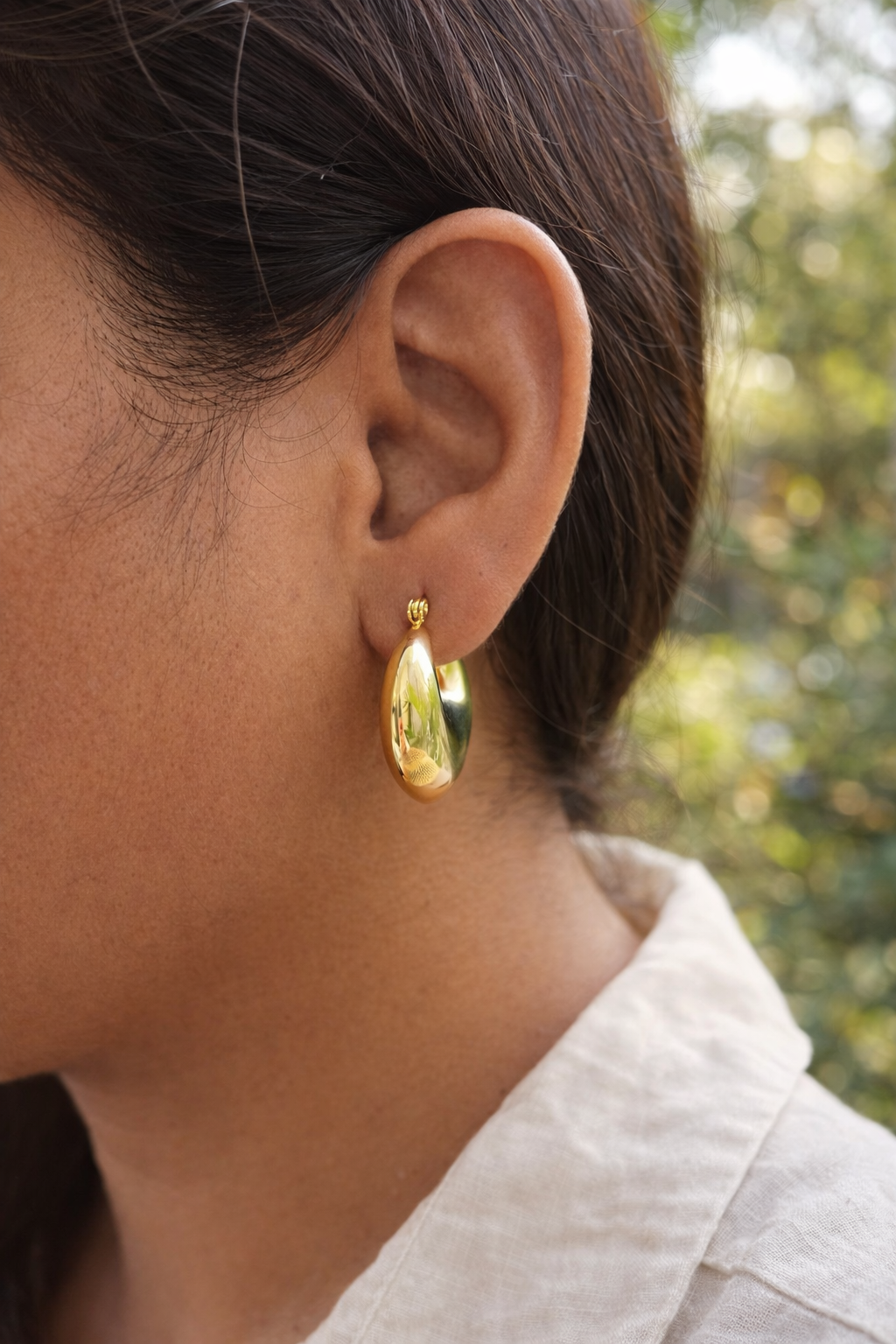 Anti-Tarnish, Ashaarya, Ashaarya Jewels, Ashaarya Jewellery, Gold earring worn by a person with a blurred natural background
