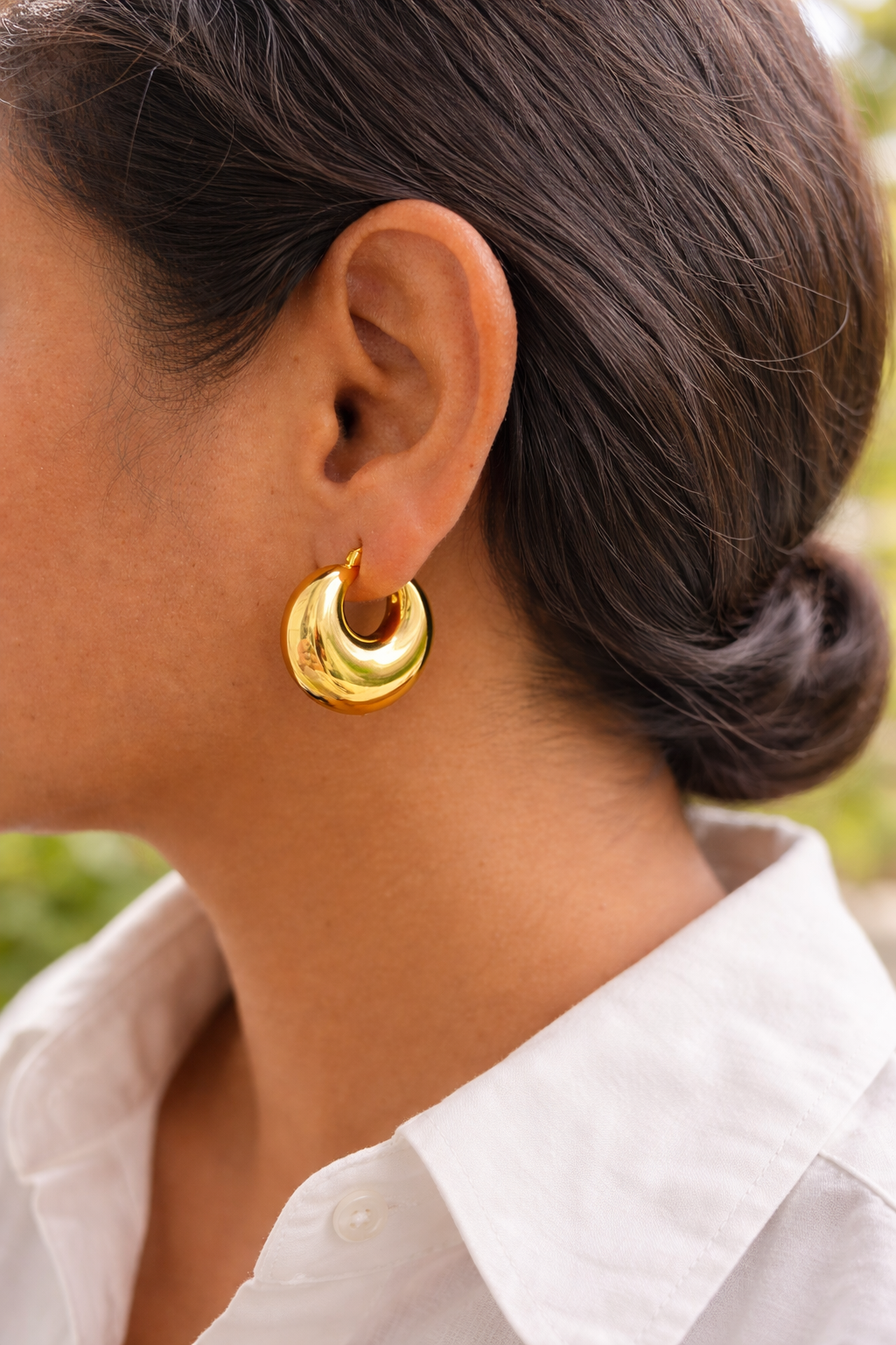Anti-Tarnish, Ashaarya, Ashaarya Jewels, Ashaarya Jewellery, Close-up of a person wearing gold hoop earrings with a blurred background