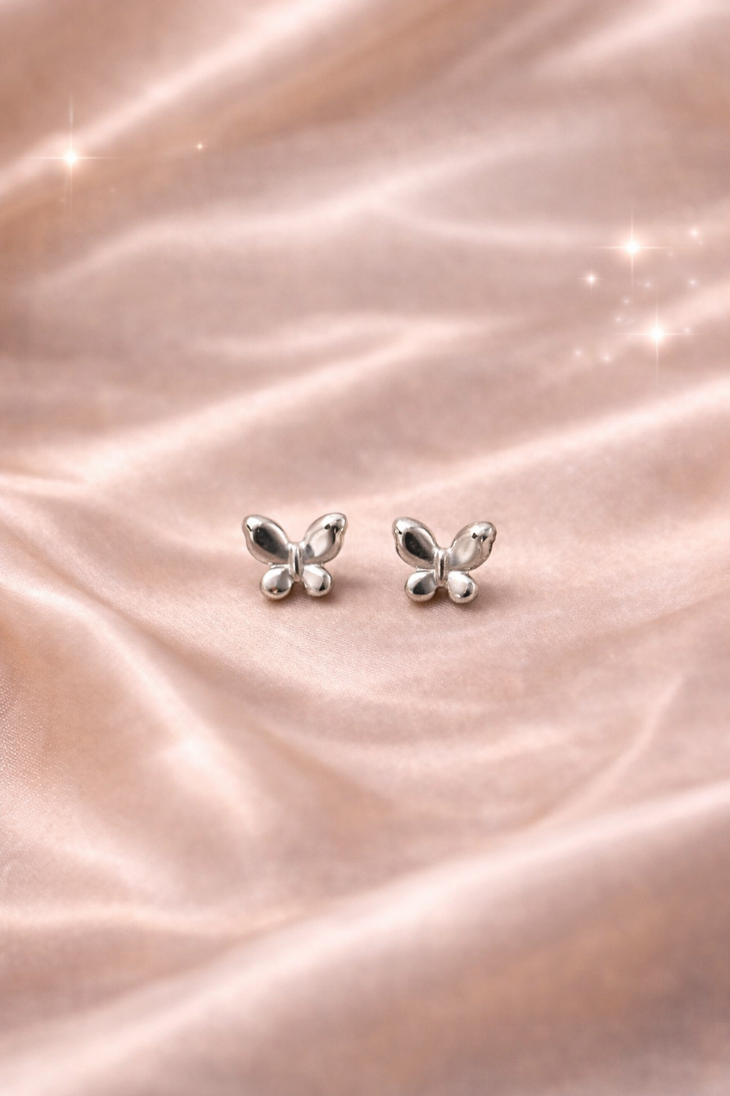 Ashaarya, Ashaarya Jewels, Ashaarya Jewellery, Butterfly-shaped earrings on a soft pink fabric background