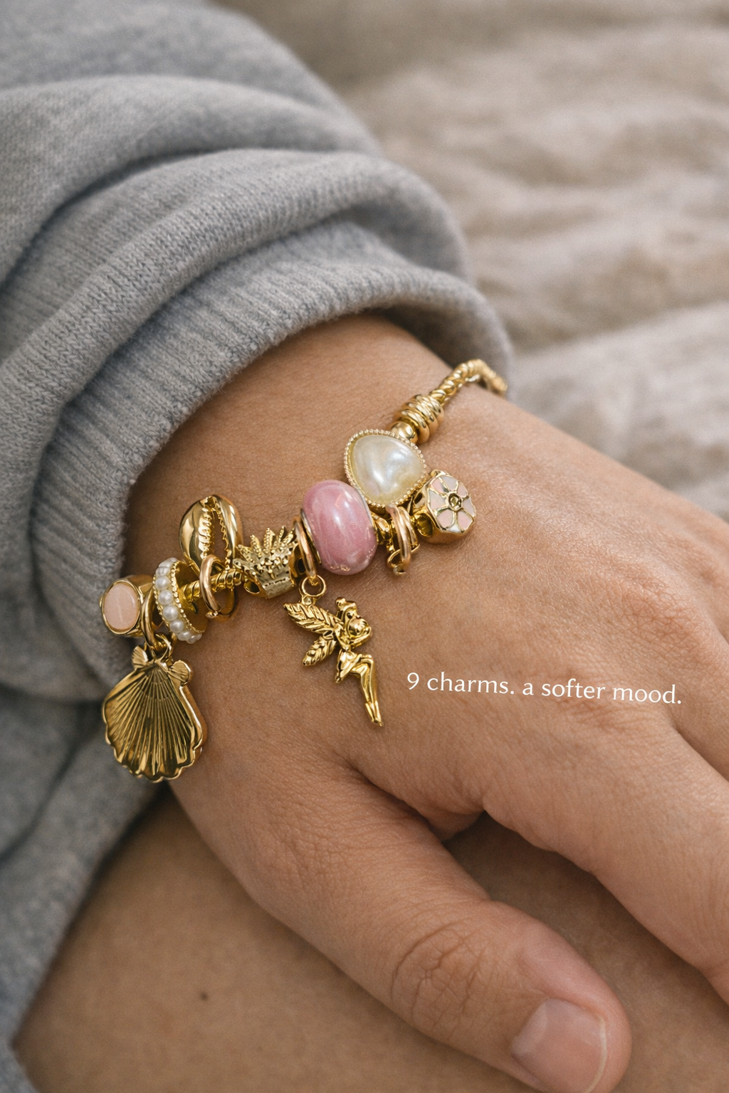 Anti-Tarnish, Ashaarya, Ashaarya Jewels, Ashaarya Jewellery,Gold bracelet with charms on a wrist, wearing a gray sleeve.