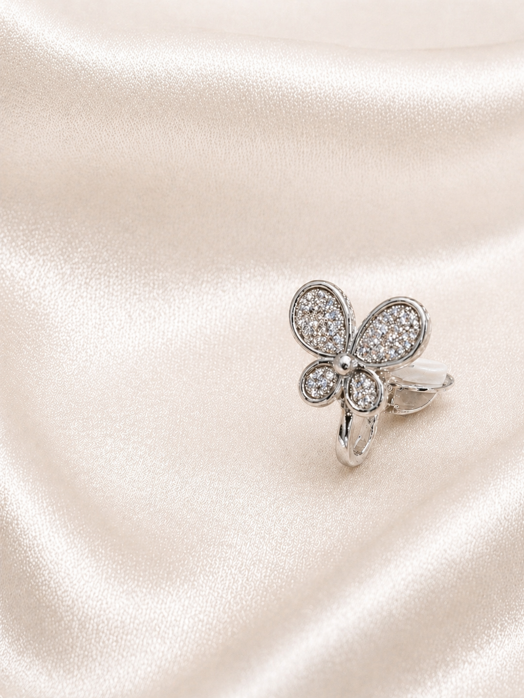 Silver butterfly-shaped earring with clear stones on a satin surface.Elegant butterfly earrings with smooth single diamonds anti-tarnish comfort jewellery for sensitive ears