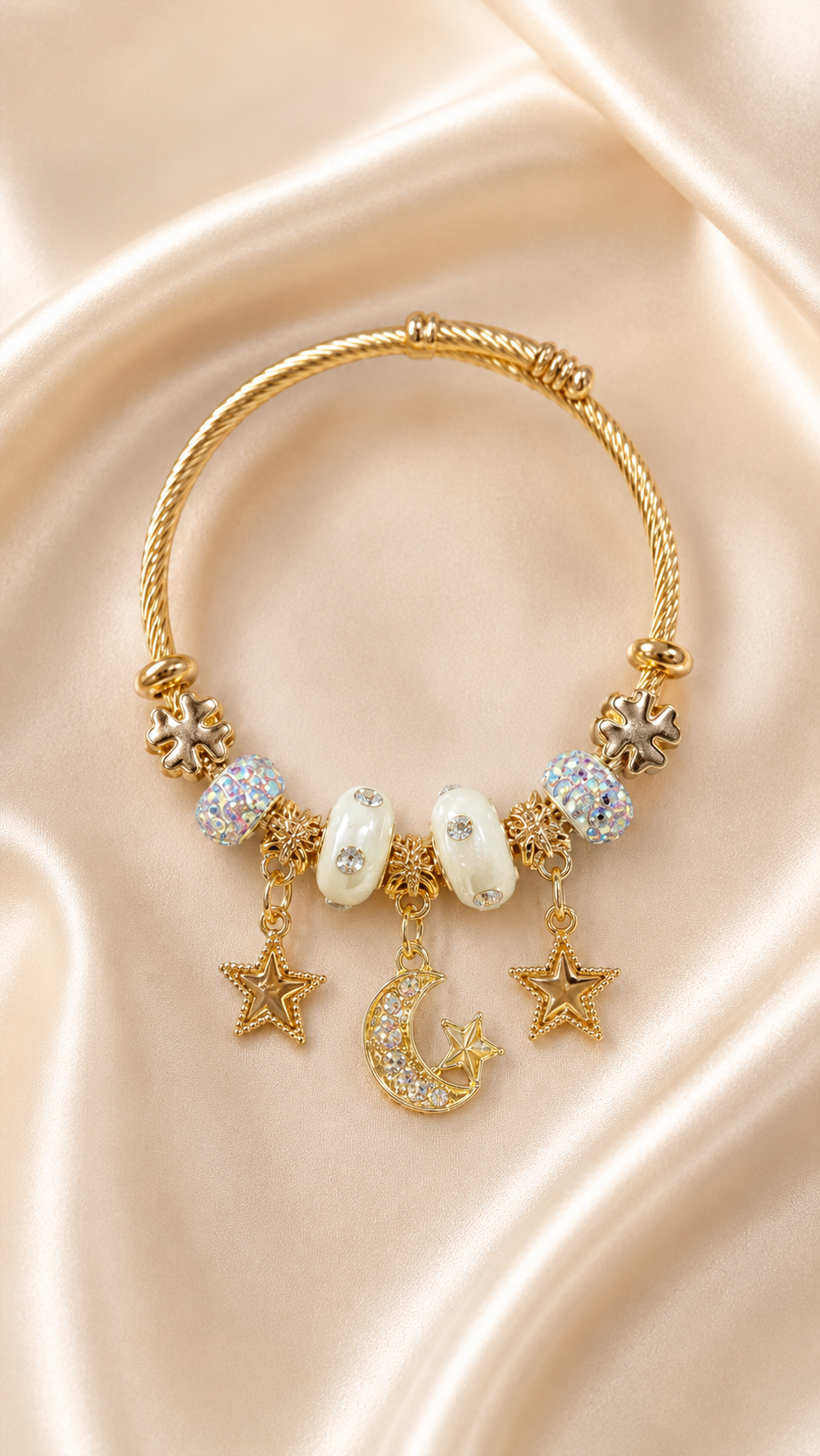 Gold bracelet with star, moon, and pearl charms on a beige fabric background