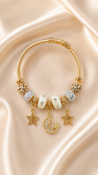 Gold bracelet with star, moon, and pearl charms on a beige fabric background