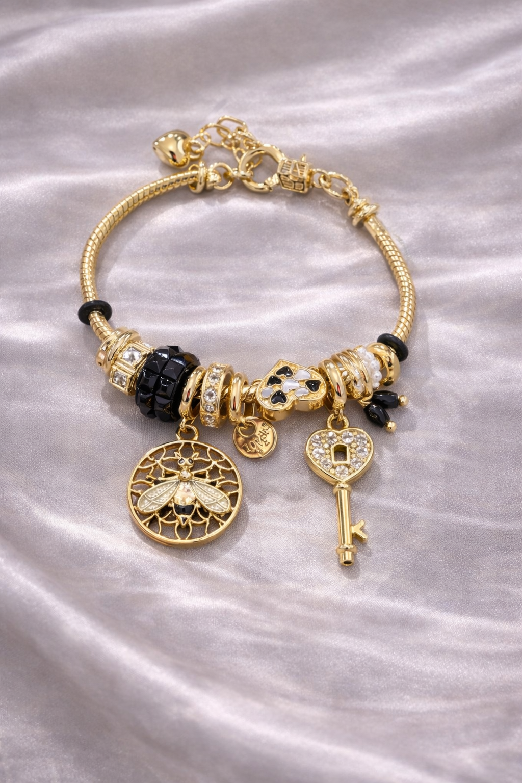 Anti-tarnish charm bracelets for women by Ashaarya featuring bee charm, heart lock key charm, black crystal beads and pearl accents designed as comfort jewellery.