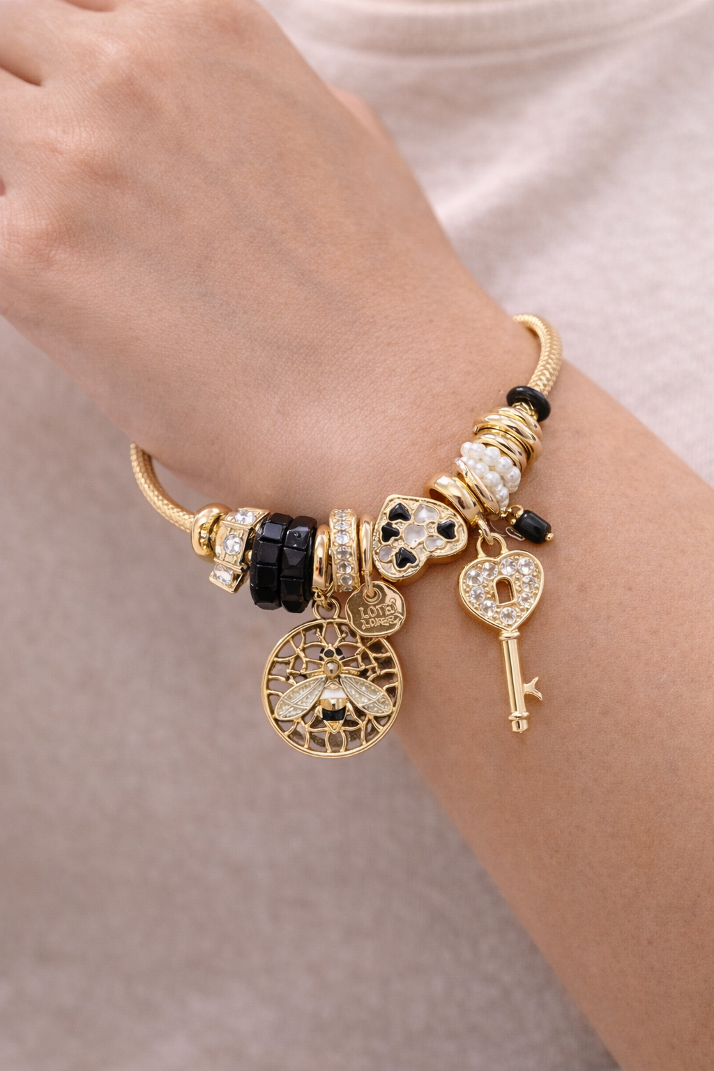 Anti-tarnish charm bracelets for women by Ashaarya featuring bee charm, heart lock key charm, black crystal beads and pearl accents designed as comfort jewellery.