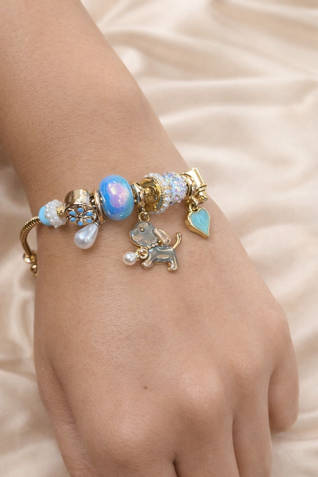 Anti-tarnish aqua charm bracelet with dog pendant and heart charm on gold snake chain – comfort jewellery by Ashaarya. Bracelet with charms on a wrist against a soft background