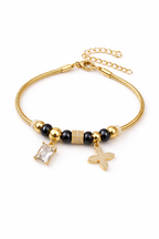 Anti-tarnish comfort jewellery charm bracelet for women with American diamond charms, gold tone beads and black stone beads – Ashaarya demi-fine charm bracelet close-up showing emerald cut stone charm and floral diamond charm