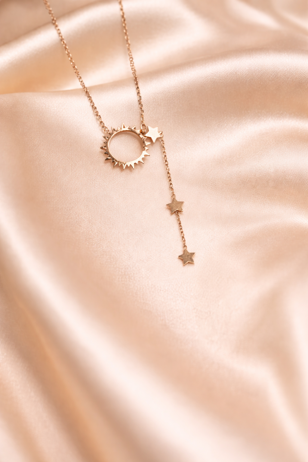 Ashaarya_anti tarnish, charm bracelet, Rose gold necklace with star and circular pendant on a soft pink fabric background