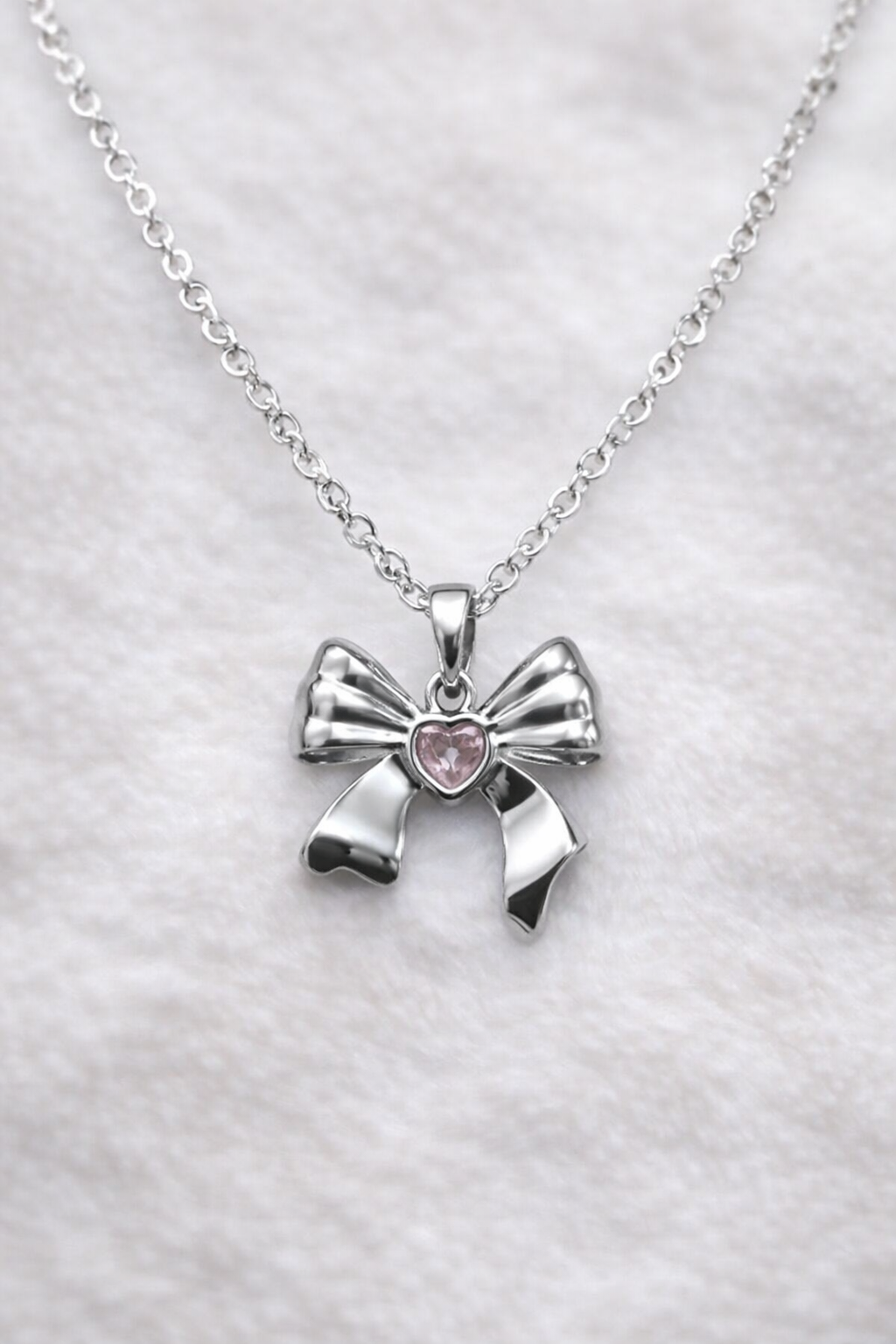 Anti tarnish necklace, Ashaarya, Charm bracelets, Ashaarya Jewels, Ashaarya jewellery, Silver bow-shaped pendant with a pink heart on a white background