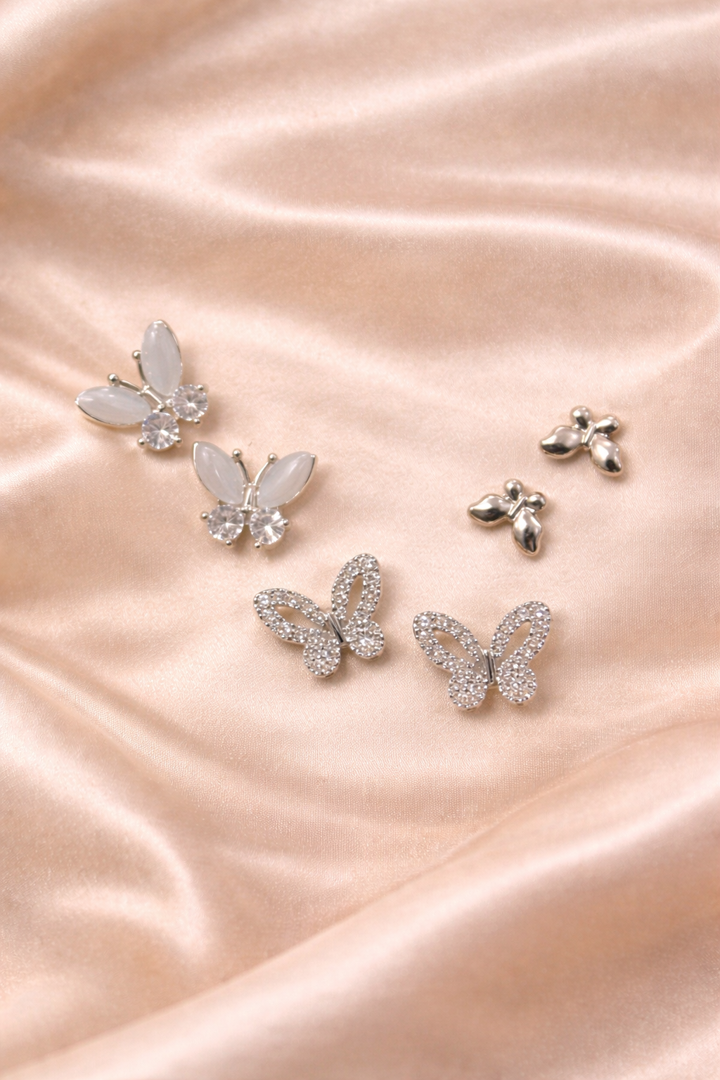 Ashaarya, Ashaarya Jewels, Ashaarya Jewellery, Butterfly-shaped earrings on a pink satin background