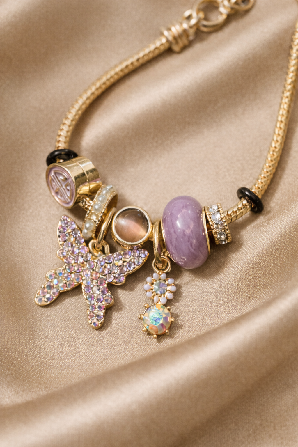 Charm bracelet, ashaarya, ashaarya bracelets, ashaarya jewels, ashaarya jewellery, Necklace with various charms on a beige fabric background