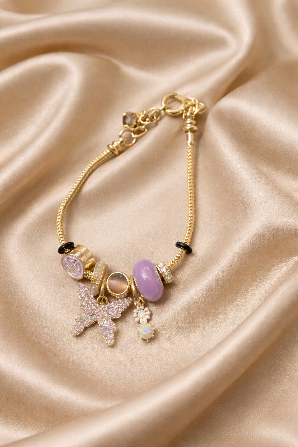 Charm bracelet, ashaarya, ashaarya bracelets, ashaarya jewels, ashaarya jewellery,Gold bracelet with charms on a beige satin background