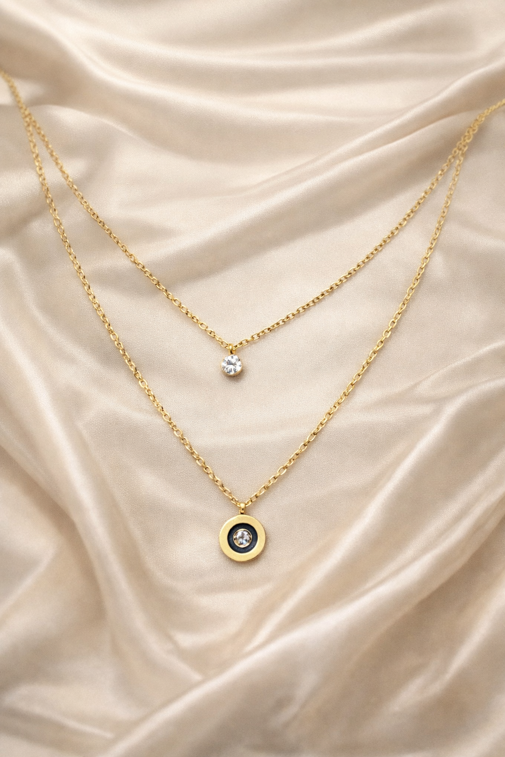 dual layer, anti tarnish, ashaarya, ashaarya jewels, ashaarya jewellery, charm bracletes, Two gold necklaces with pendants on a beige satin background