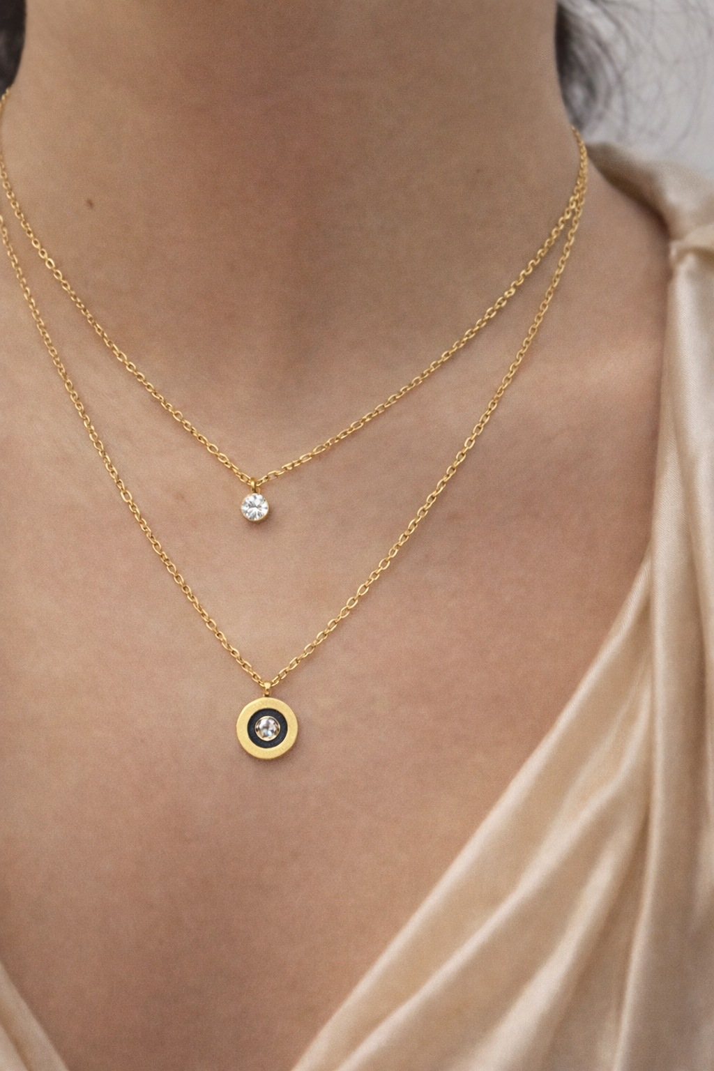 dual layer, anti tarnish, ashaarya, ashaarya jewels, ashaarya jewellery, charm bracletes,Two gold necklaces with gemstone pendants on a person wearing a beige top.