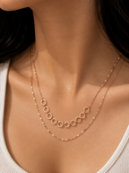 A close-up of a model wearing a delicate rose gold double-layer necklace. The top layer features a row of small, connected open hexagonal rings, while the bottom layer is a fine beaded chain. rose gold necklace for women, dual layer necklace, layered necklace for women, geometric necklace, honeycomb necklace, minimalist necklace, rose gold jewellery, anti tarnish necklace, lightweight necklace, stainless steel necklace, everyday necklace, office wear necklace, dainty layered necklace, comfort jewellery, pre