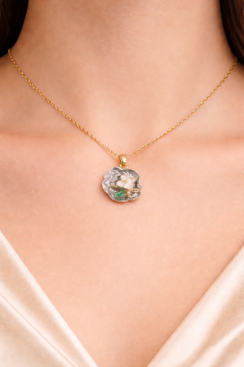 Love pearl necklace, Ashaarya, Ashaarya jewels, Ashaarya jewellery, anti-tarnish necklace Gold necklace with a floral pendant on a person wearing a white top.