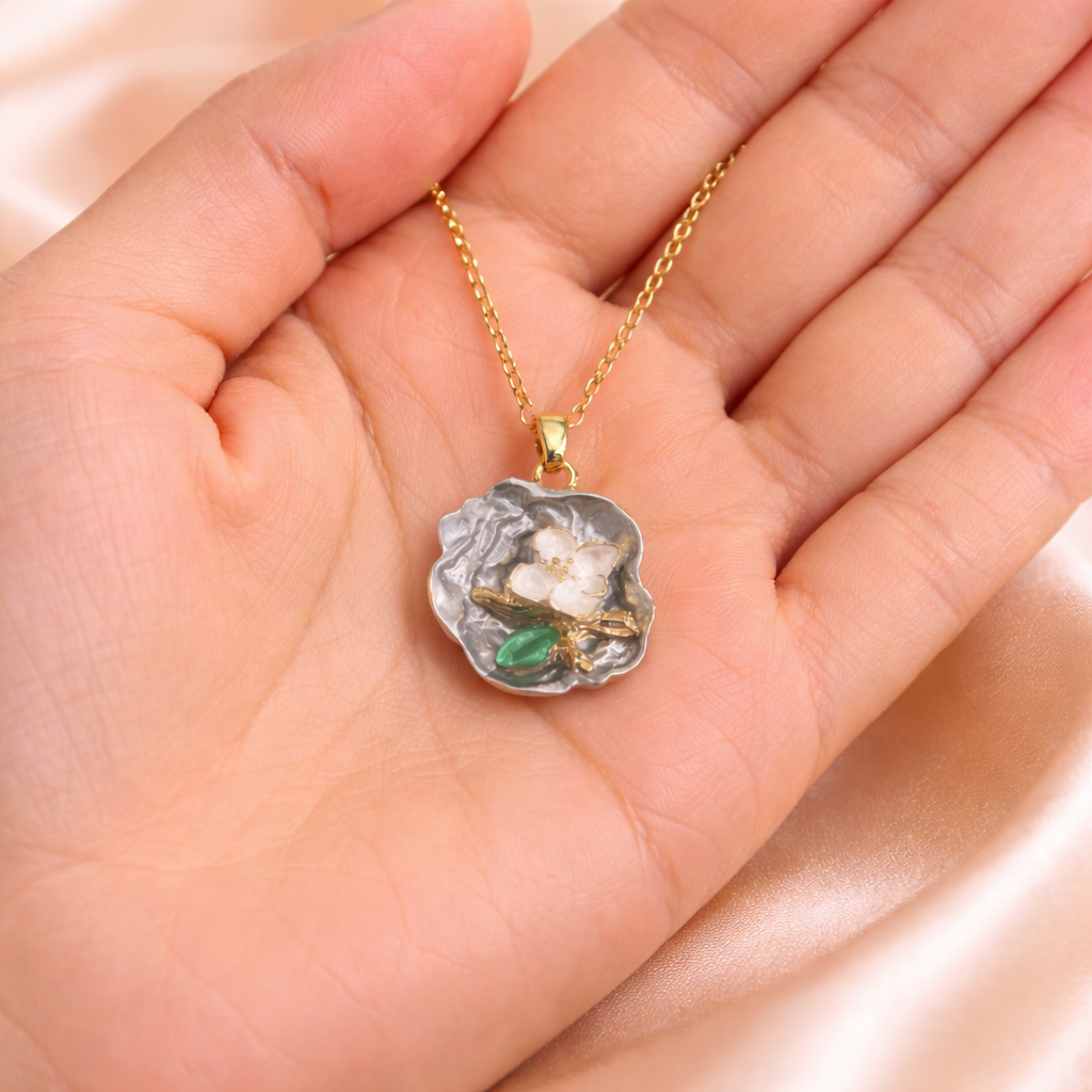 Love pearl necklace, Ashaarya, Ashaarya jewels, Ashaarya jewellery, anti-tarnish necklace floral pendant held in a hand against a soft pink background