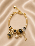 Noir Wisdom Charm Bracelet by Ashaarya featuring owl, key, pearl shell and black crystal charms in 18KT gold plated 316L stainless steel.