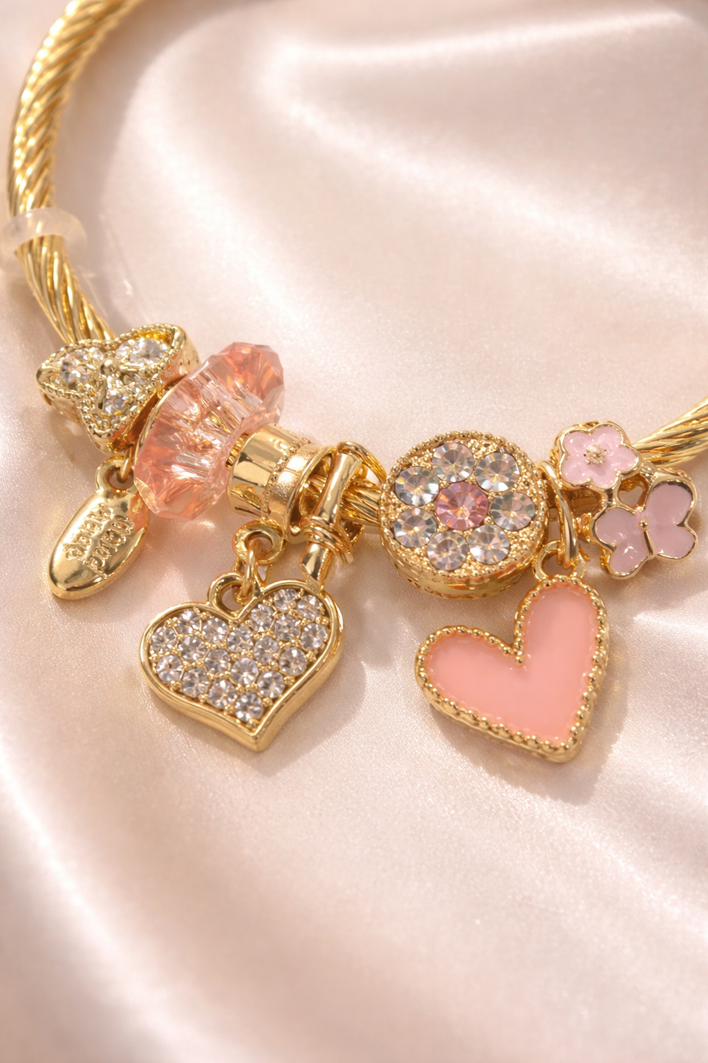 Close-up of charms on anti-tarnish demi-fine charm bracelets jewellery featuring pink heart charms, crystal charms and floral charms for women