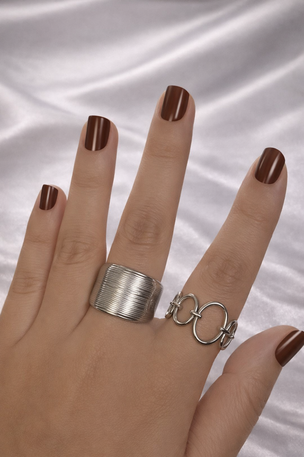 Adjustable anti-tarnish silver stackable rings set with bold coil band and open link design – lightweight comfort jewellery, Hand wearing two silver rings on a white fabric background