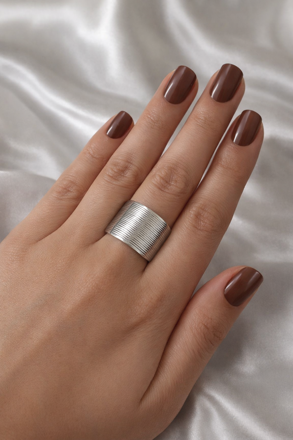 Adjustable anti-tarnish silver stackable rings set with bold coil band and open link design – lightweight comfort jewellery, Hand with a silver ring on a white fabric background